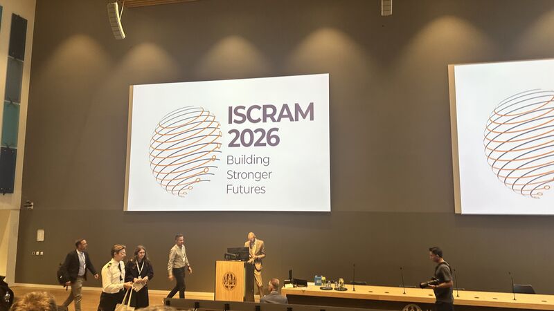 ISCRAM 2026 행사 화면과 여러 진행자가 보이는 강당 프로그램 장면.