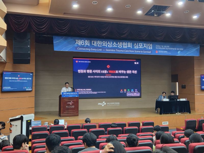 제6회 대한외상소생협회 심포지엄 행사 배너, TECC 강연 화면, 청중이 함께 보이는 강당 전경.